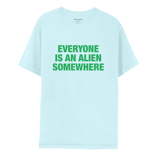 Front: This is Jonny’s shirt. Fabric is a very pale blue. EVERYONE IS AN ALIEN SOMEWHERE printed in dark green. The text is large and bold, in 3 lines: EVERYONE, IS AN ALIEN, SOMEWHERE.