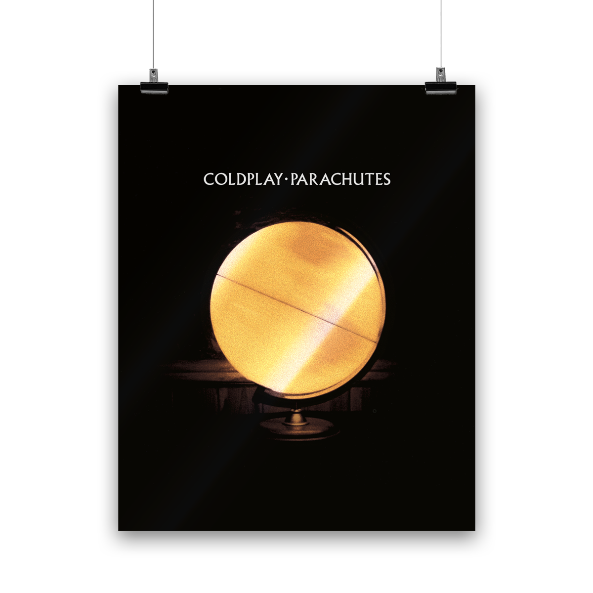Image 1:
A yellow globe represents the earth, illuminated from within. The center is a bright, luminous yellow; it transitions to a darker, muted red towards the edges, with golden and amber hues. It has reddish patches as continents, and horizontal lines running across as though the globe is spinning. The globe is a lamp, mounted on a stand. It has a black and dark brown background. COLDPLAY, PARACHUTES is written in white